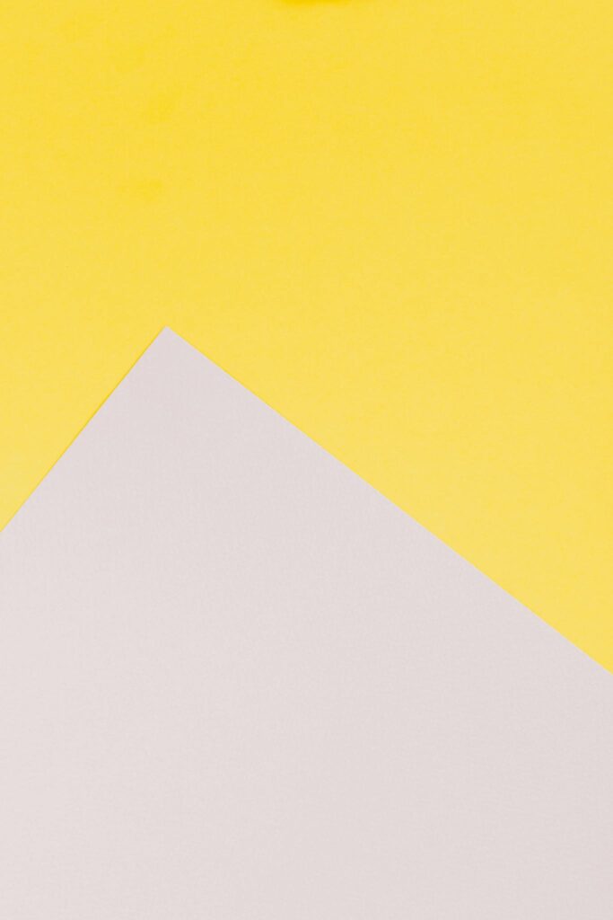 Minimalist composition featuring a white paper on a vibrant yellow background, perfect for creative copy space.